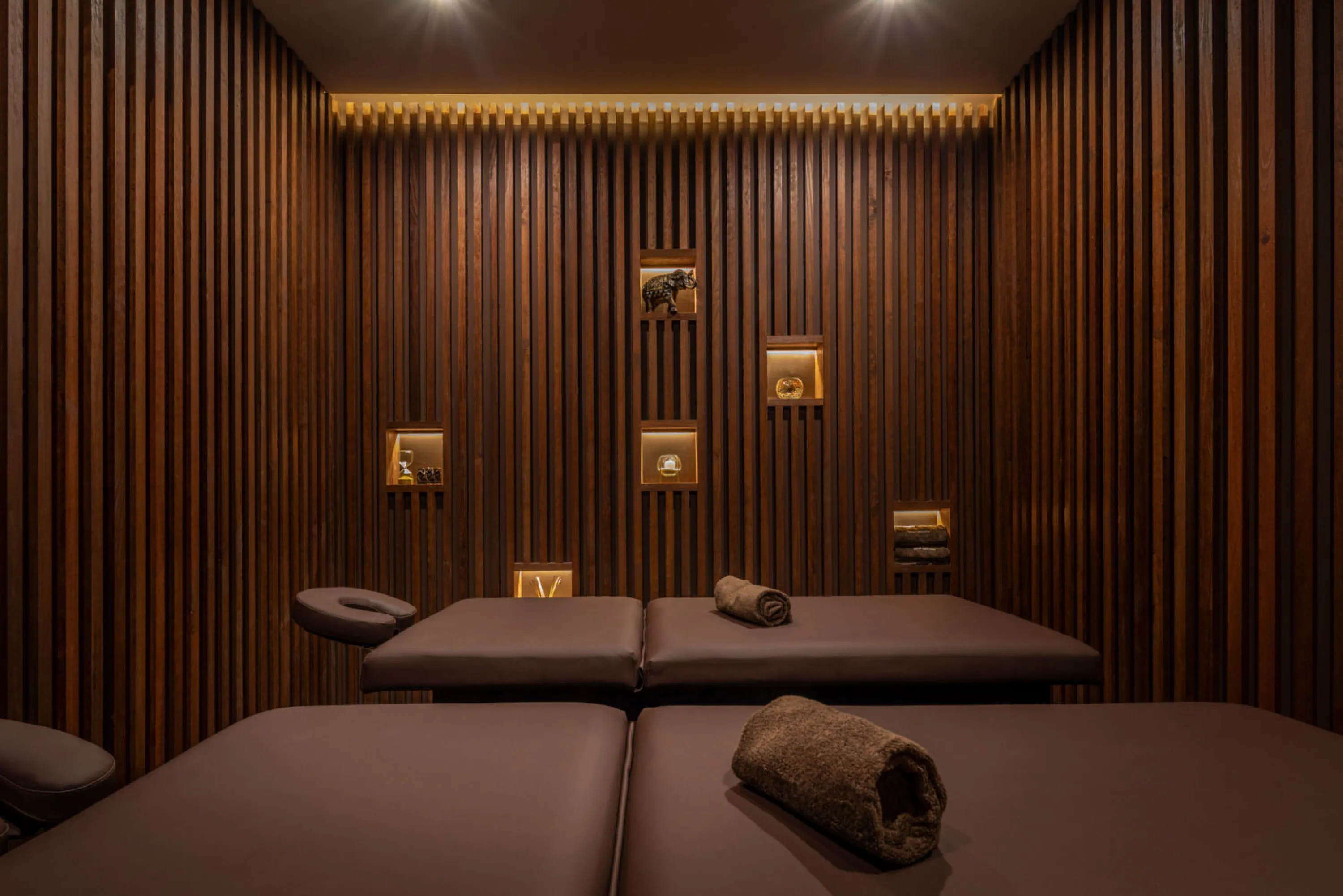 A biophilic treatment room with wood panelled walls and soft lighting.