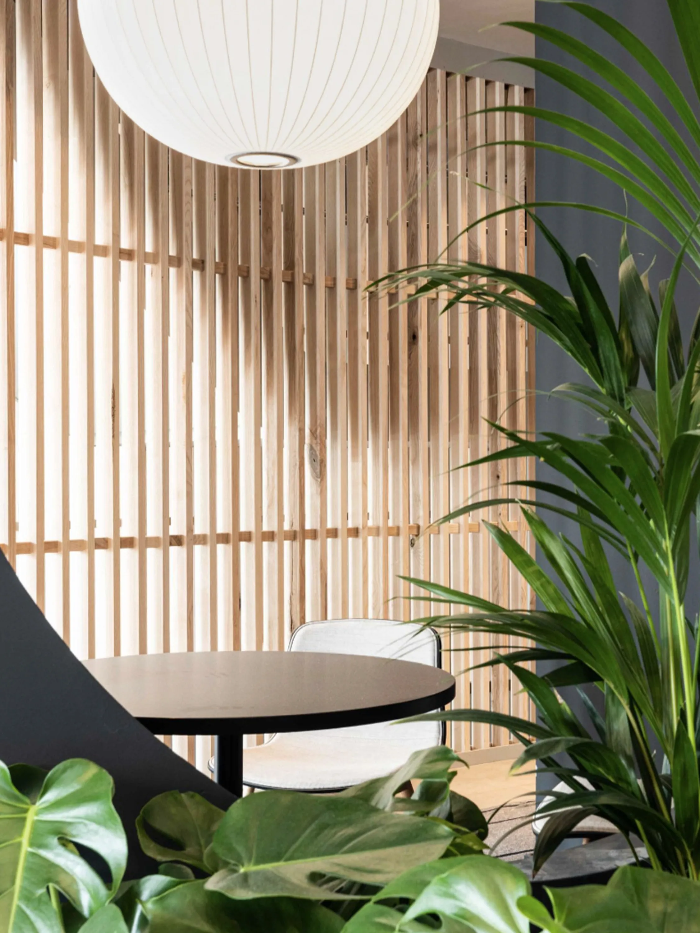 Private working nook surrounded by plants and screened with wood panelling.